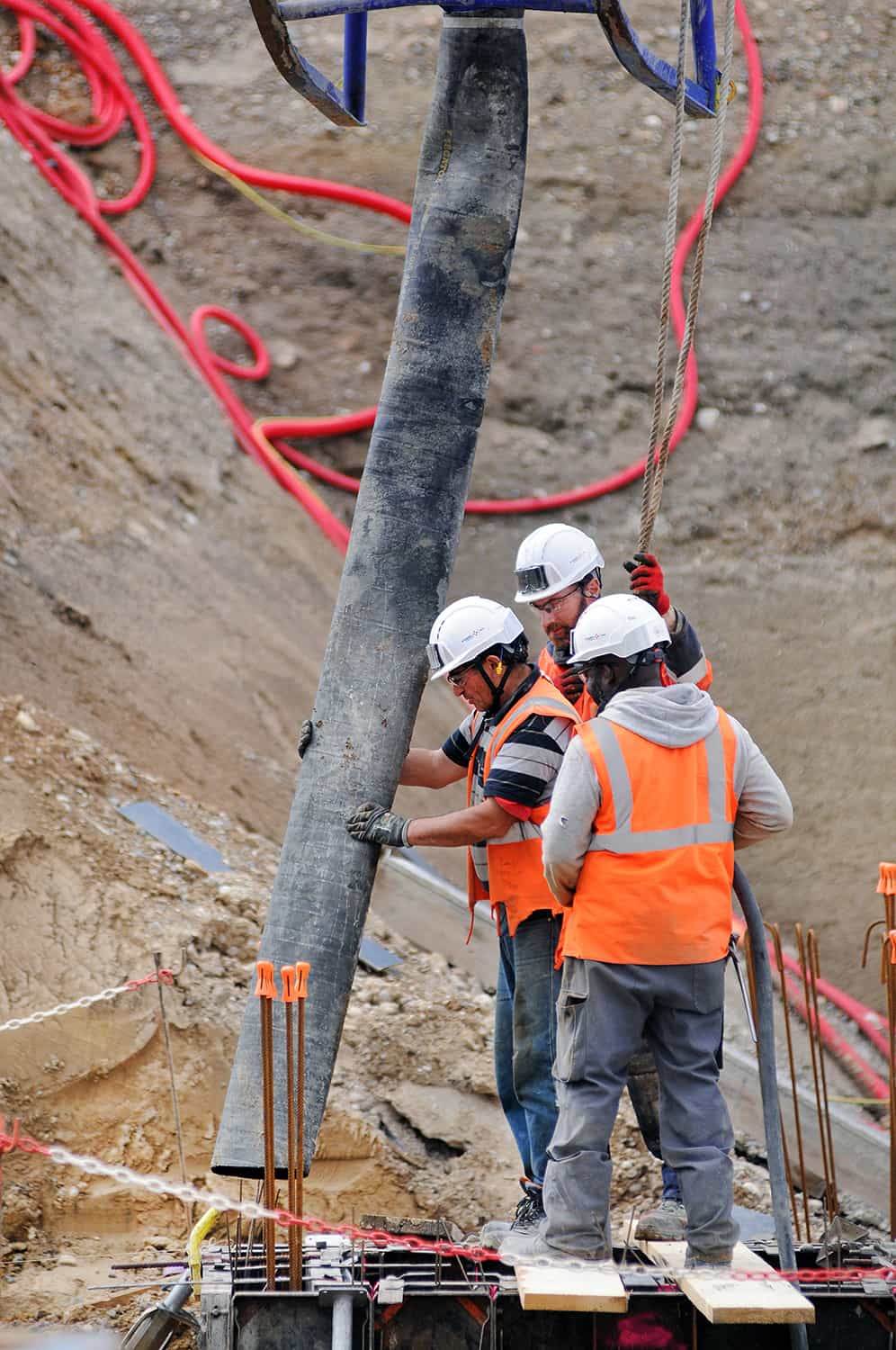 photographie corporate de trois coffreurs sur un chantier manipulant un tuyau © francois nussbaumer