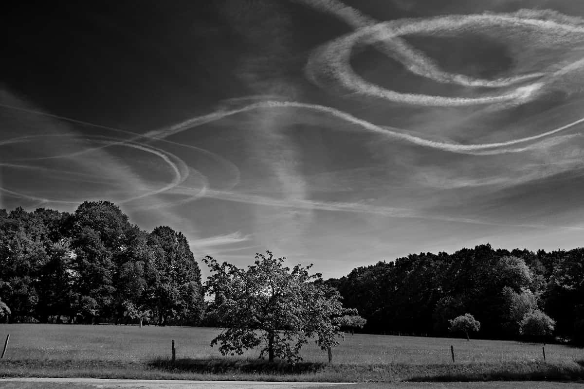 photographie noir et blanc de traces blanches laissées par des avions dans le ciel © francois nussbaumer