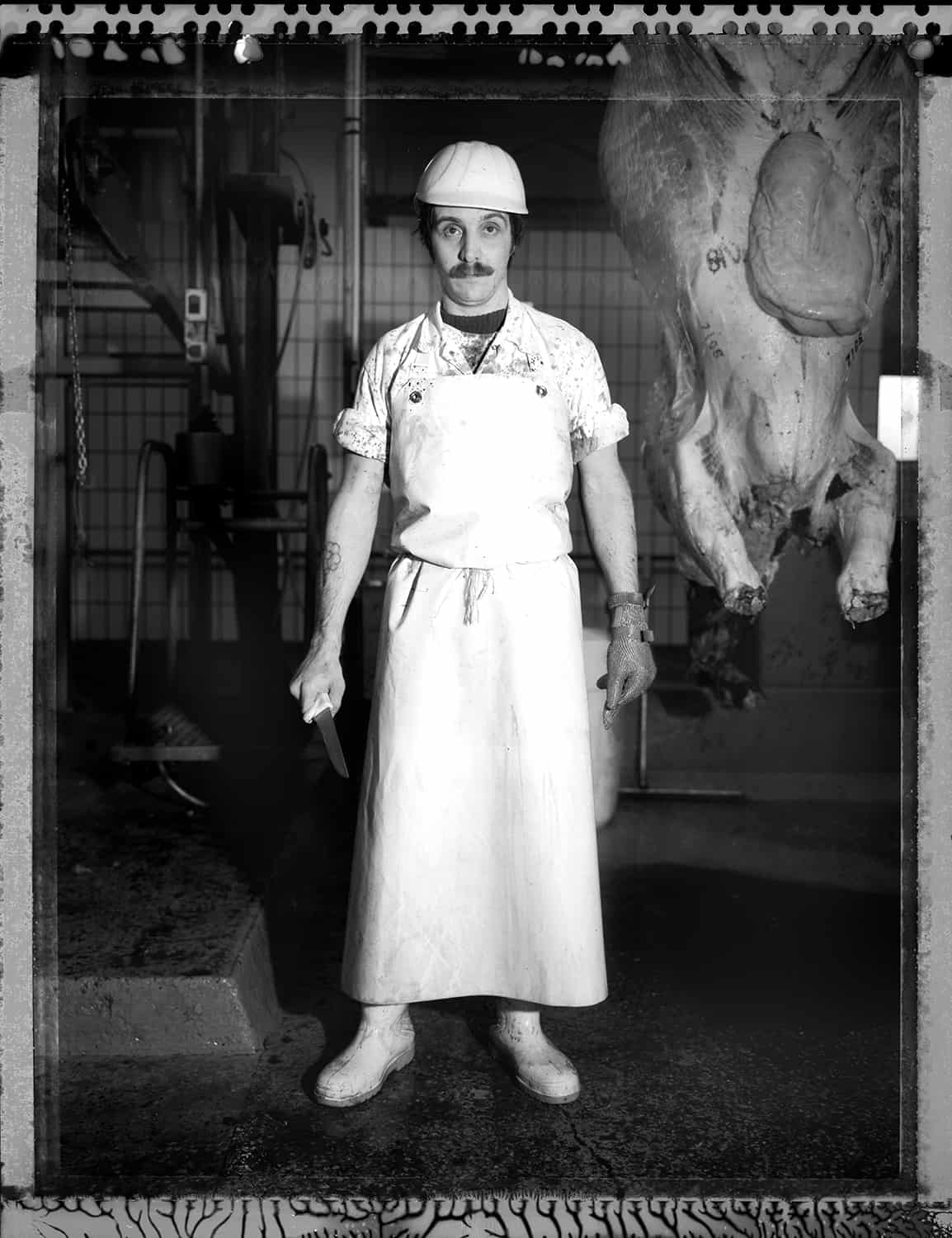 photo noir et blanc d'un tueur aux abattoirs se tenant devant un cadavre de vache © francois nussbaumer